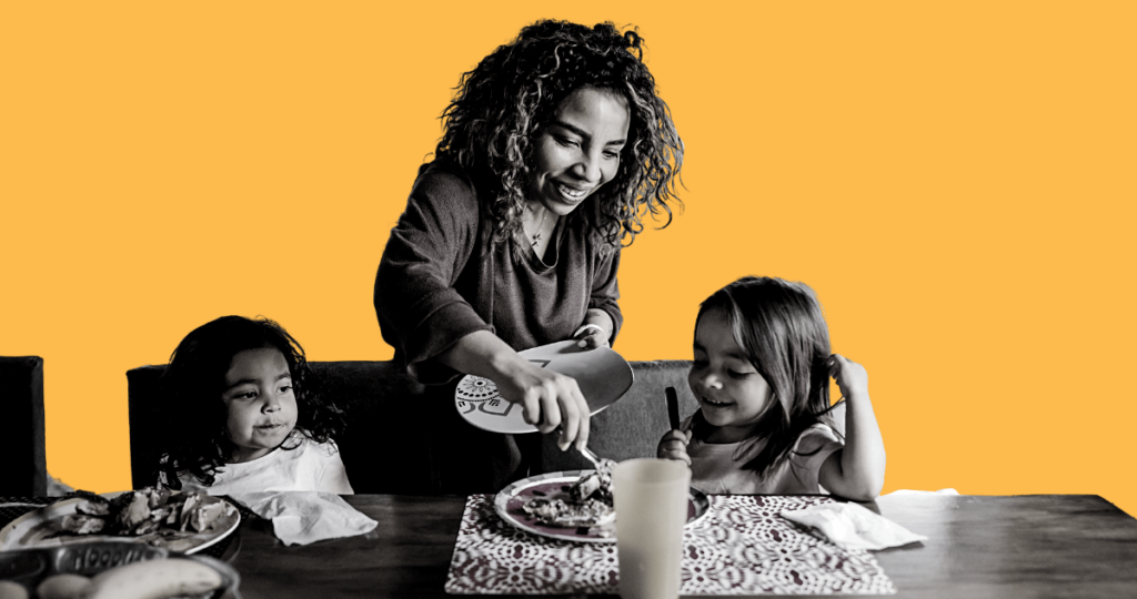 Mother feeding her two children at a dinner table,