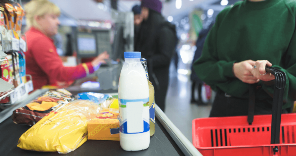 Woman standing at a grocery checkout holding a shopping basket.