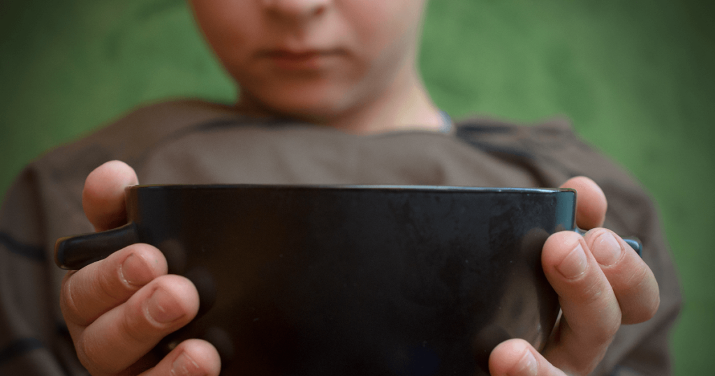 Young child holding out a bowl to the camera.