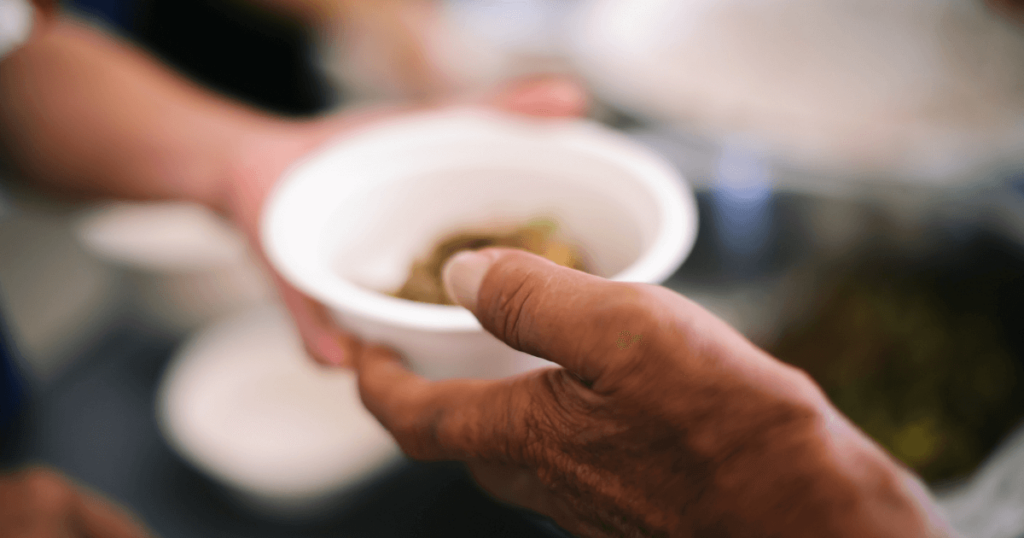 A person handing someone a bowl of food.