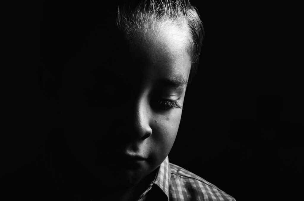 Black and white image of a young child looking sad.