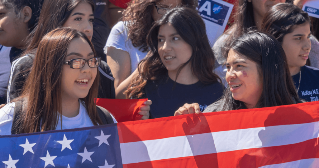 A group of young Latina women holding a US flag.